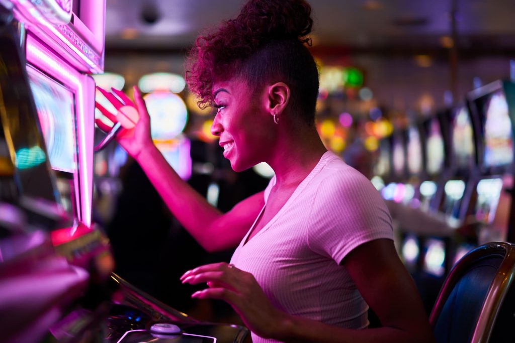 Happy woman gambling at a casino playing slot machine